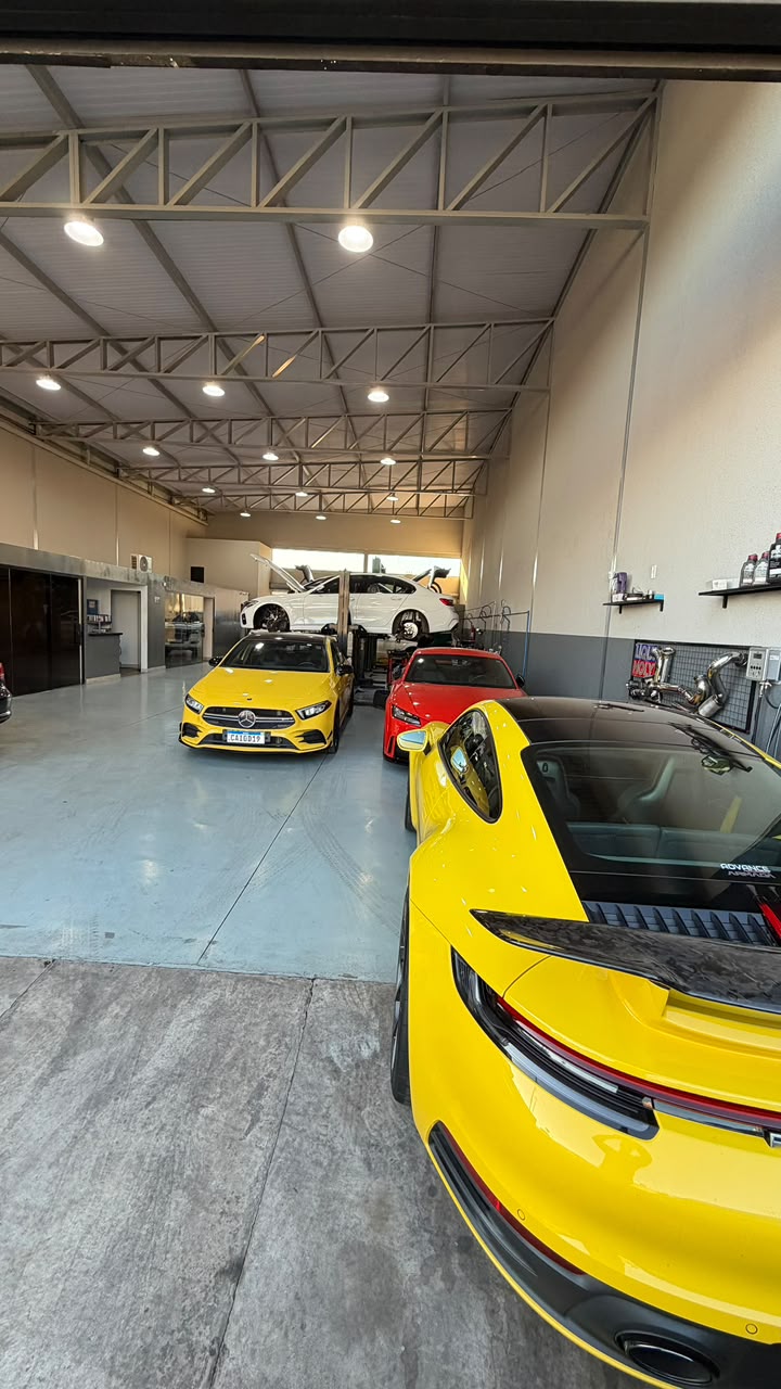 Porsche 911 amarelo e Mercedes-AMG A35 no interior da oficina Advance Performance